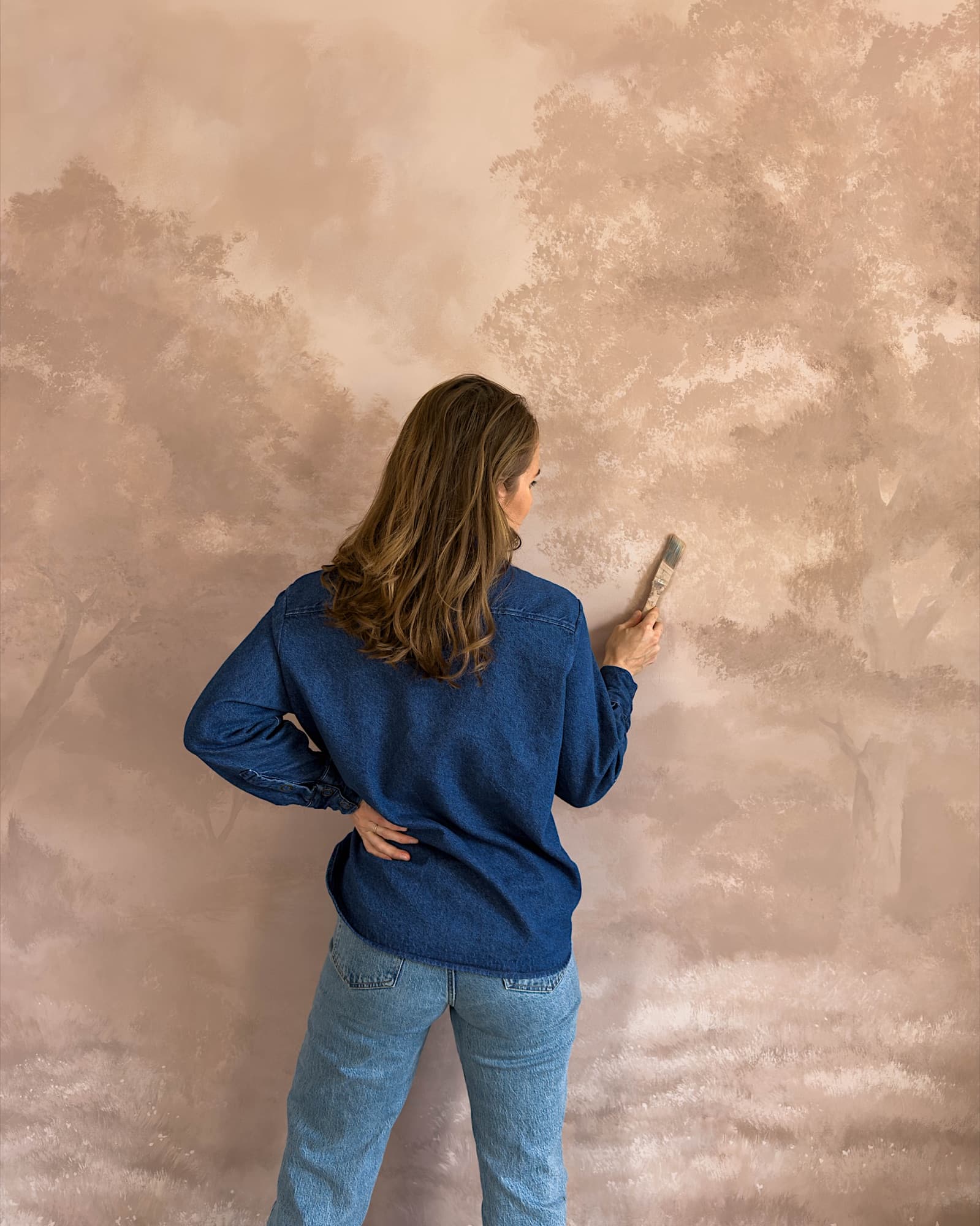 Anna at work, facing a sepia mural in progress.