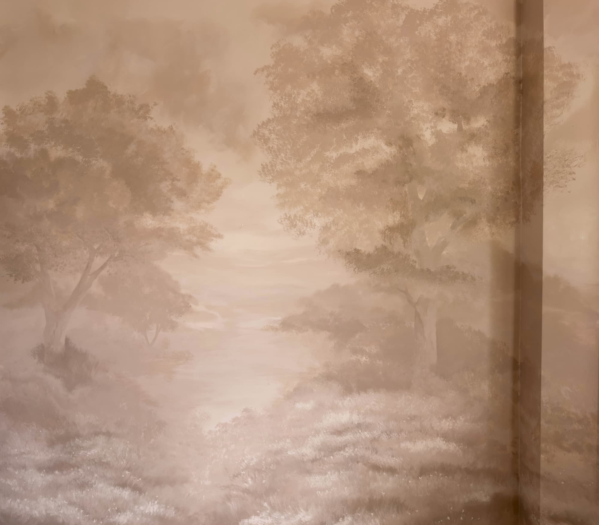 Wide view of a sepia landscape mural across a studio wall.